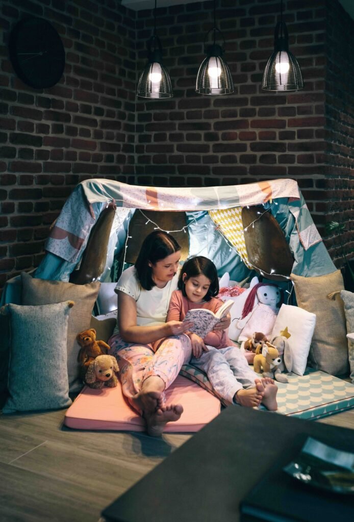 Mother and daughter reading under a blanket fort
