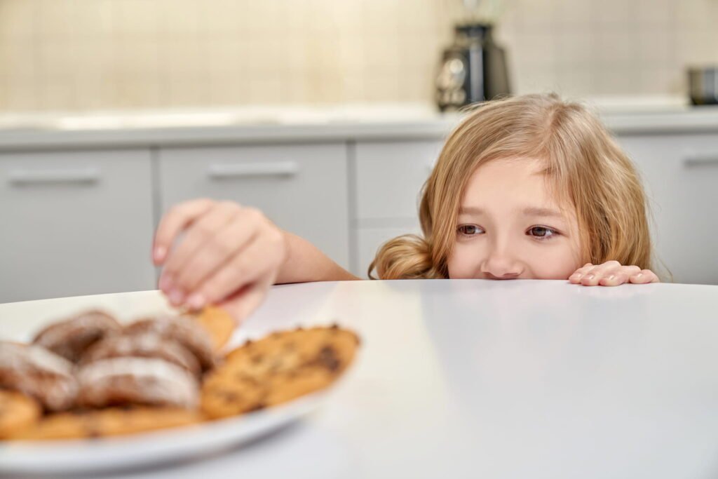 Child trying to sneak a cookie from the table